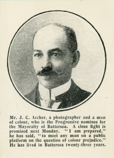 John Archer A black and white dappled photo in a cirlce of John Archer, ,a man with a moustache and a balding head. The caption reads 'Mr J C Archer, a photographer and a man of colour, who is the Progressive nominee for the Mayoralty of Battersea. A close fight is promised next Monday.